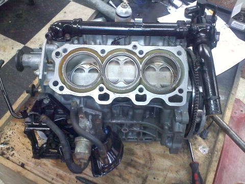 1993 Ford Probe - Close-up view of an engine block, showing three cylinders and associated plumbing, resting on a wooden surface.