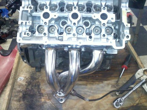1993 Ford Probe - Close-up of an engine block and exhaust manifold, with tools visible on the workbench.