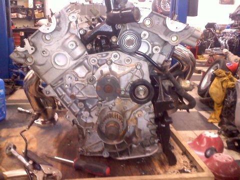 1993 Ford Probe - Engine block and exhaust manifold on a workbench, with tools nearby.