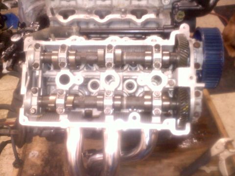 1993 Ford Probe - Close-up of an engine's cylinder head, showing camshafts and a blue timing gear. The Supermotors.net logo is visible in the lower right cor…