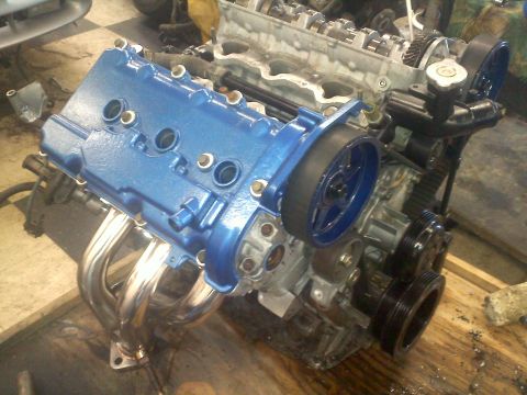1993 Ford Probe - Engine assembly with blue valve cover and chrome headers, likely undergoing repair or modification.