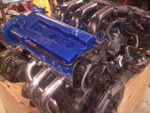 1993 Ford Probe - Close-up of a Ford engine, a blue painted valve cover and chrome exhaust headers.
