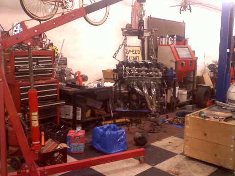 1993 Ford Probe - A disassembled engine is suspended by a red engine hoist in a workshop environment.