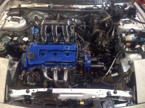 1993 Ford Probe - Engine bay a blue painted engine block and chrome exhaust manifold.
