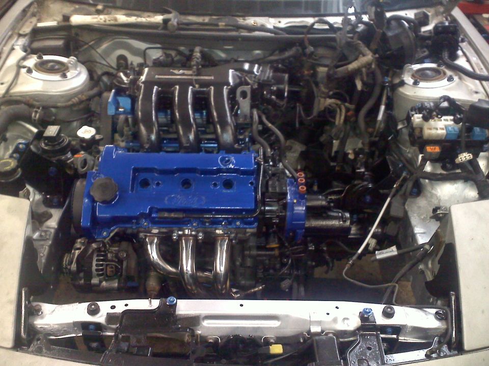 Engine bay with blue painted engine block and chrome exhaust manifold