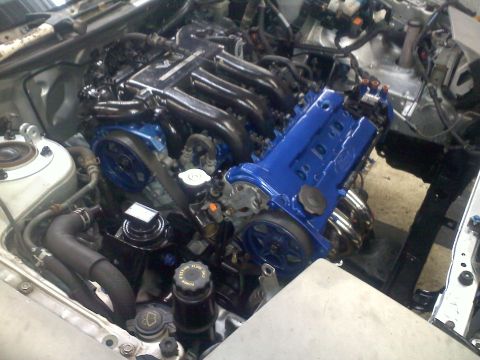 1993 Ford Probe - Engine bay with a blue painted valve cover and intake manifold. Some hoses and belts are visible.