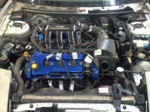 1993 Ford Probe - Engine bay view showing the engine components, including blue valve covers and exhaust headers.