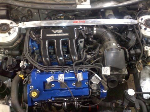 1993 Ford Probe - Engine bay of a 1993 Ford Probe, a V6 engine with blue valve covers and a chrome strut bar.