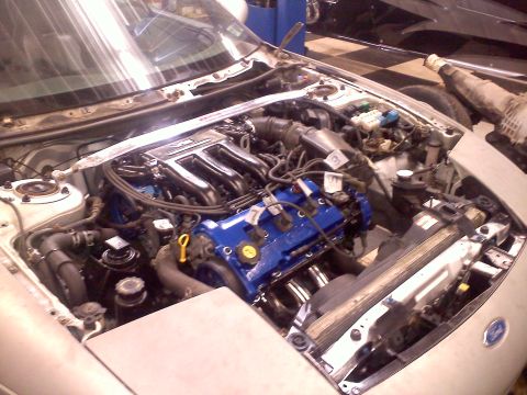 1993 Ford Probe - The engine bay of a car, blue painted valve covers and chrome headers.