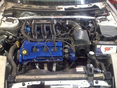 1993 Ford Probe - Engine bay of a 1993 Ford Probe GT, showing the V6 engine with custom blue valve covers.