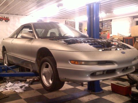 1993 Ford Probe - Silver 1993 Ford Probe GT undergoing service in a garage, with its hood raised to reveal the engine.
