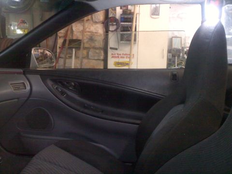 1993 Ford Probe - Interior view of a driver's side door panel and seat, with a sign visible in the background.
