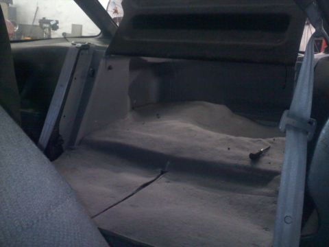 1993 Ford Probe - The dusty interior rear cargo area of a vehicle is shown, with a seatbelt visible on the right.