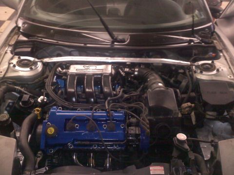 1993 Ford Probe - The engine bay of a car, a V6 engine with blue painted components and a strut tower brace.