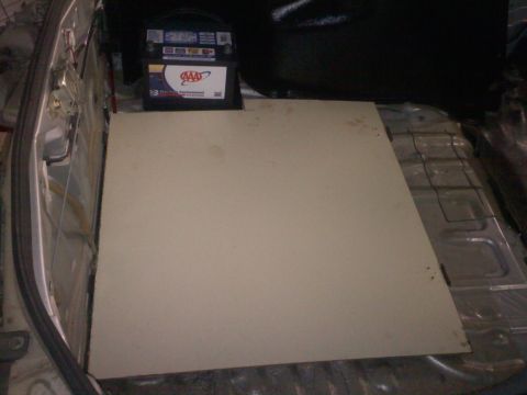 1993 Ford Probe - The interior of a car trunk shows a beige panel and a car battery.