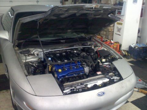 1993 Ford Probe - The front of a silver 1993 Ford Probe is visible with its hood open, revealing the engine bay.