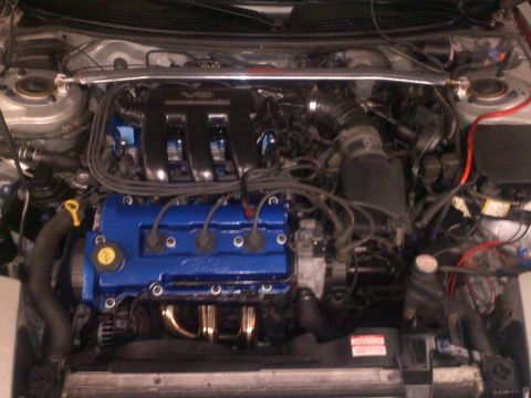 1993 Ford Probe - Engine bay view blue Ford valve covers and a chrome exhaust manifold.