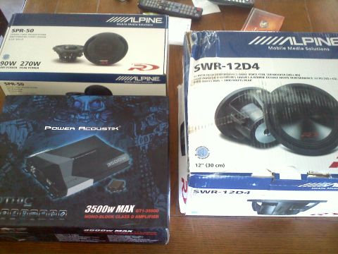 1993 Ford Probe - Several boxes of car audio equipment, including speakers and an amplifier, are arranged on a table.
