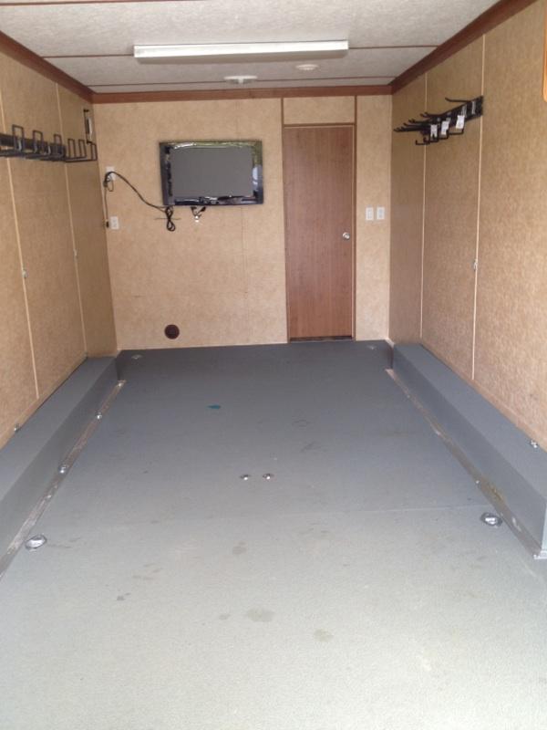 Interior of a trailer with a mounted TV and storage hooks