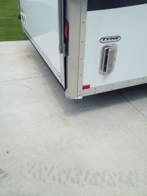 1967 Ford Mustang - The rear corner of a white enclosed trailer is shown, a TAG logo and a silver latch.