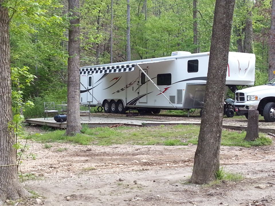 White fifth wheel trailer with checkered awning and graphics, parked next to a white pickup truck