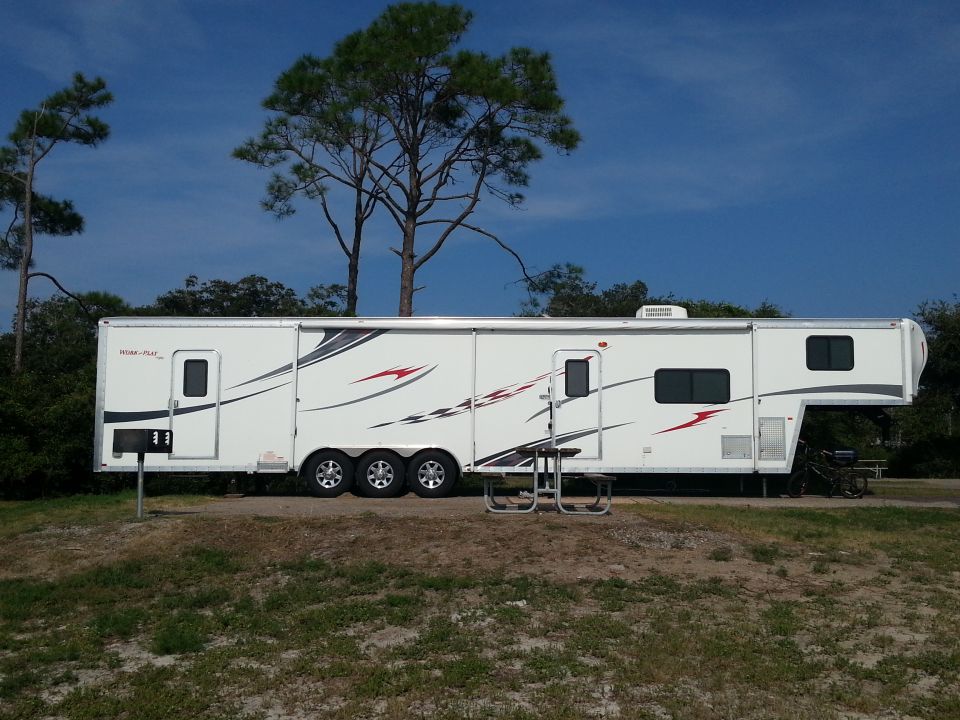 white toy hauler RV parked outside with a picnic table in front