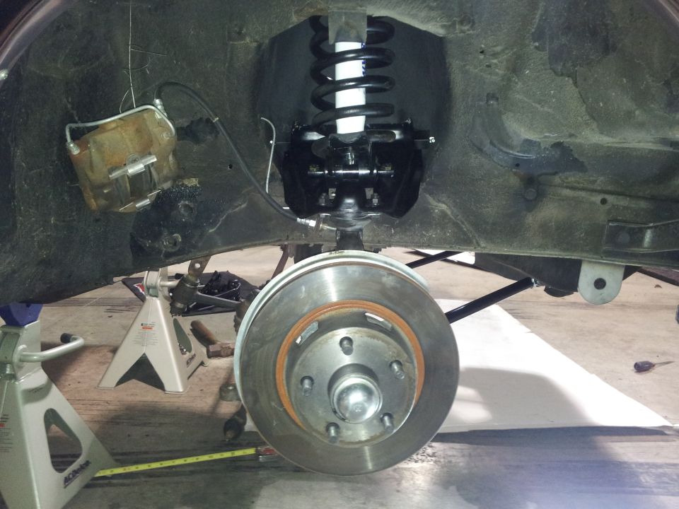 close-up of car's front suspension and brake rotor, car is on jack stands
