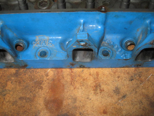 Blue painted engine cylinder head with casting numbers C9AE and 8090. Surface is worn