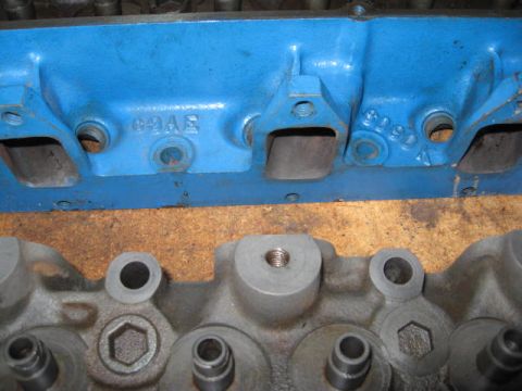 1963 Ford Galaxie - Close-up of two engine cylinder heads, one painted blue with casting numbers '99AE' and '8090K'.