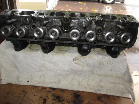 1963 Ford Galaxie - A used engine cylinder head is shown, with visible valve springs and retainers, placed on a towel.