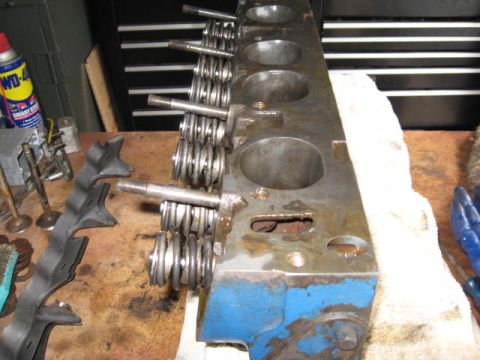 1963 Ford Galaxie - Close-up of an engine cylinder head, showing valves and springs, on a workbench.