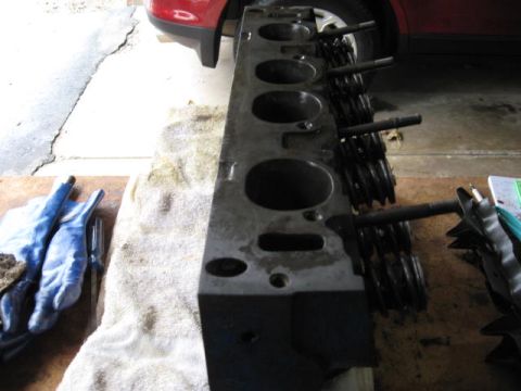 1963 Ford Galaxie - Close-up of an engine cylinder head, showing valves and springs, with work gloves nearby.