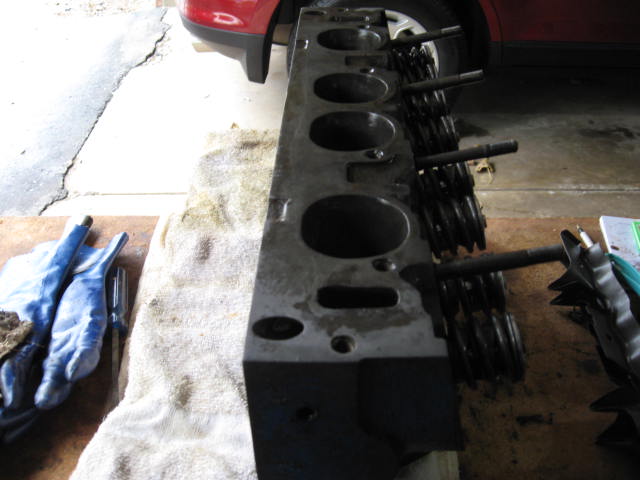 engine cylinder head with valves and springs, on a table with gloves and a rag
