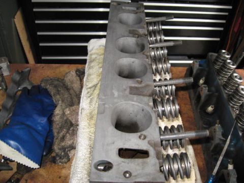 1963 Ford Galaxie - Two engine cylinder heads are visible, one in the foreground and another to the right, resting on a workbench.