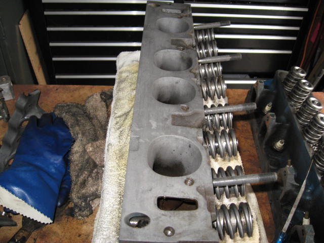 Engine cylinder heads with valve springs and bolts on a workbench