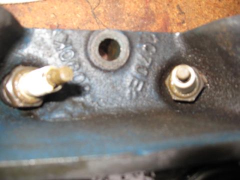 1963 Ford Galaxie - A close-up view of an engine component, showing a spark plug and a bolt. Some casting numbers are visible on the metal.
