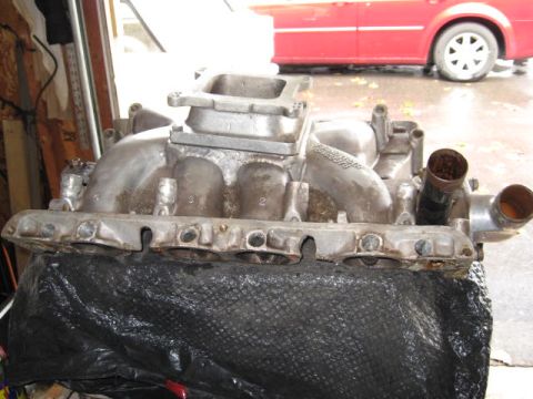 1963 Ford Galaxie - Aluminum intake manifold with visible casting numbers and ports, resting on a black cover.