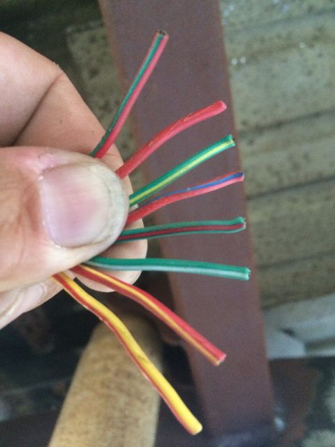 1987 Suzuki Samurai - A hand holds several electrical wires, including red, green, yellow, and blue strands.
