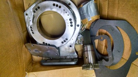 1979 Ford F-150 - A collection of automotive transmission parts, including an adapter plate and input shaft, are shown inside a cardboard box.