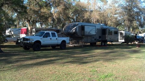 1995 Ford Bronco - White Ford F-250 Super Duty pickup truck towing a large fifth-wheel RV at a campground.