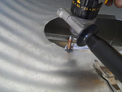 1992 Ford Bronco - A drill is used to create a hole in a metal panel, with a wrench nearby.