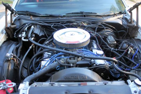 1976 Ford Ranchero - The engine bay of a vehicle is shown, with numerous hoses and wires.