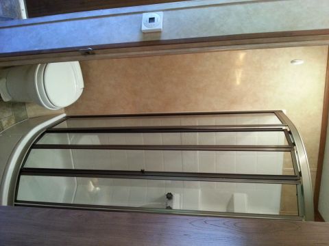 1967 Ford Mustang - Interior view of a recreational vehicle bathroom, showing a toilet and a shower stall with glass doors.