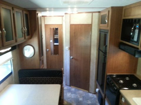1967 Ford Mustang - The interior of an RV shows a kitchen area with a microwave and stove, adjacent to a seating area and doors.