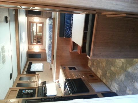 1967 Ford Mustang - Interior of an RV showing the kitchen area with a stove and cabinets, and a living space with a mattress.