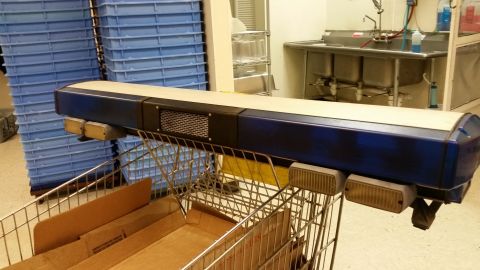 2001 Ford Crown Victoria - A light bar is mounted on a shopping cart in front of blue storage bins.