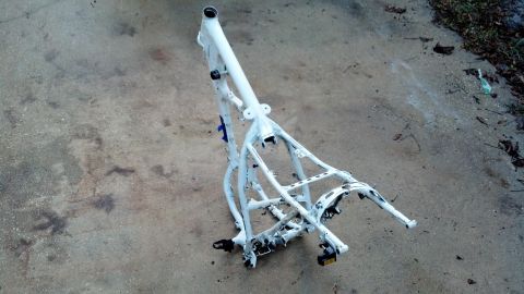 1995 Ford Bronco - A white motorcycle frame lies on a concrete surface, with some debris and grass visible in the background.