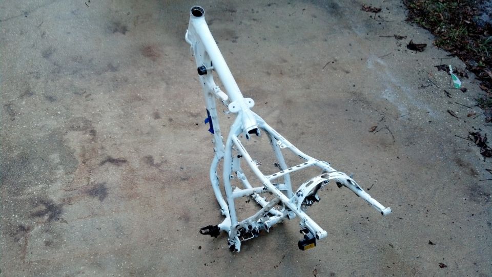 White motorcycle frame on concrete ground, viewed from a high angle