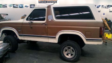 1982 Ford Bronco - Side view of a lifted 1982 Ford Bronco in a workshop.