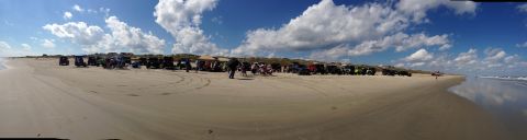 1979 Ford Bronco - A group of off-road vehicles gathered on a sandy beach under a partly cloudy sky.